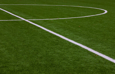 Photo of a green synthetic grass sports field with white line shot from above